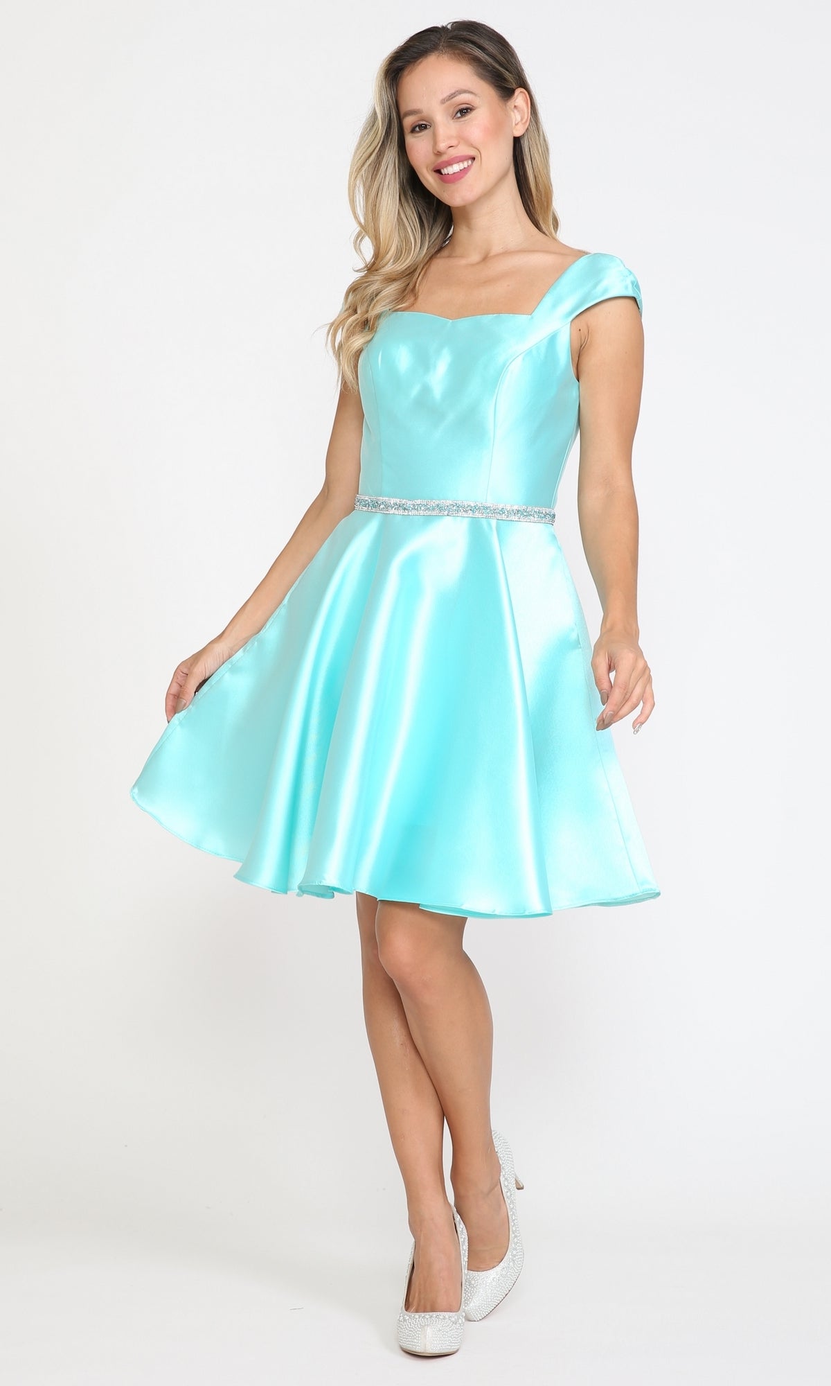 Woman models the Cap-Sleeve Short Homecoming Dress with Pockets 8416—a light blue satin dress with beaded waistband and cap sleeves, styled with white heels—perfect as an affordable party dress for any occasion.